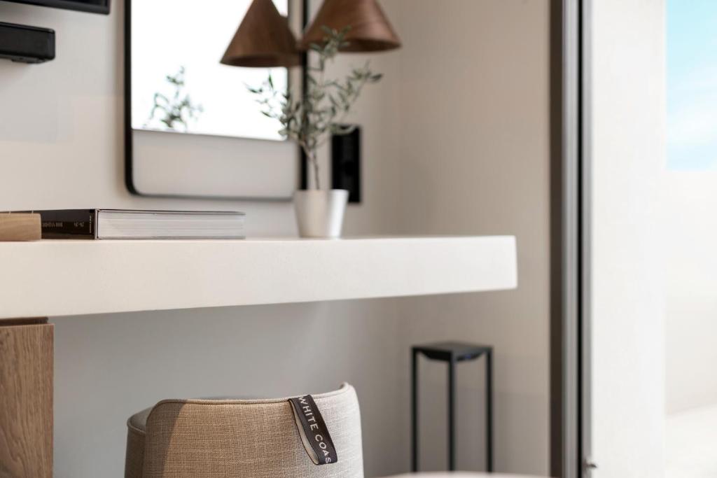 a white counter with a mirror and a chair at Domes White Coast Milos, Adults Only - Small Luxury Hotels of the World in Mytakas