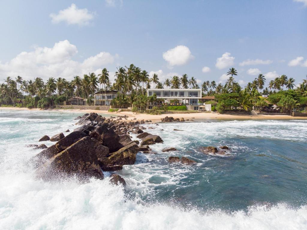 a view of a beach with waves and a building at Sielen Diva in Unawatuna