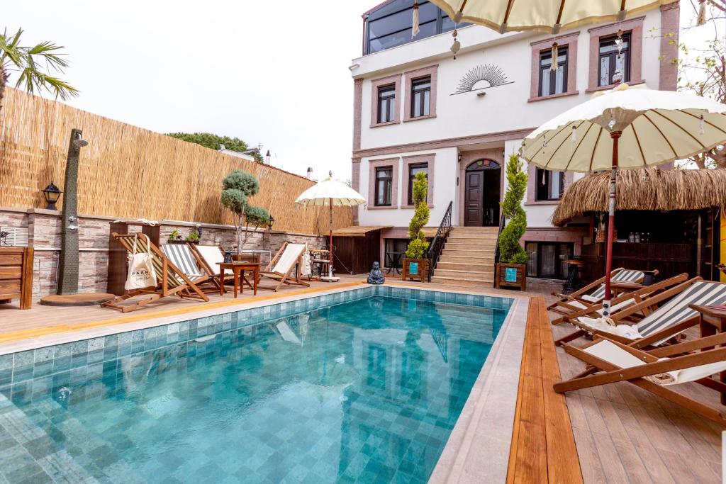 a swimming pool with chairs and an umbrella next to a house at Parna Hotel in Cunda