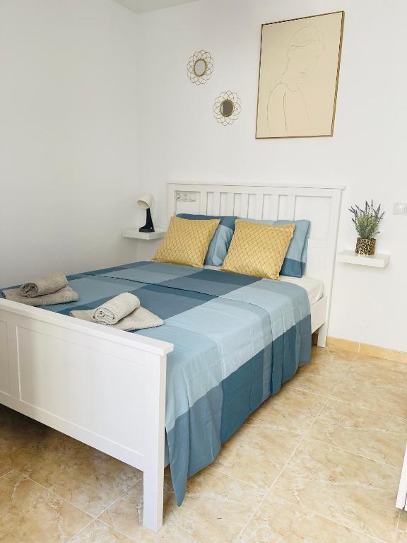 białe łóżko z niebiesko-żółtymi poduszkami w obiekcie UIM Mediterraneo Poeta 3 Wifi w mieście Puerto de Sagunto