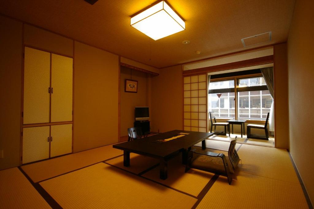 een kamer met een tafel en stoelen en een raam bij Kamogawakan in Kyoto