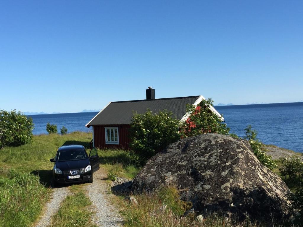 une voiture garée devant une maison près de l'eau dans l'établissement Rorbua på Toppøya, à Reine