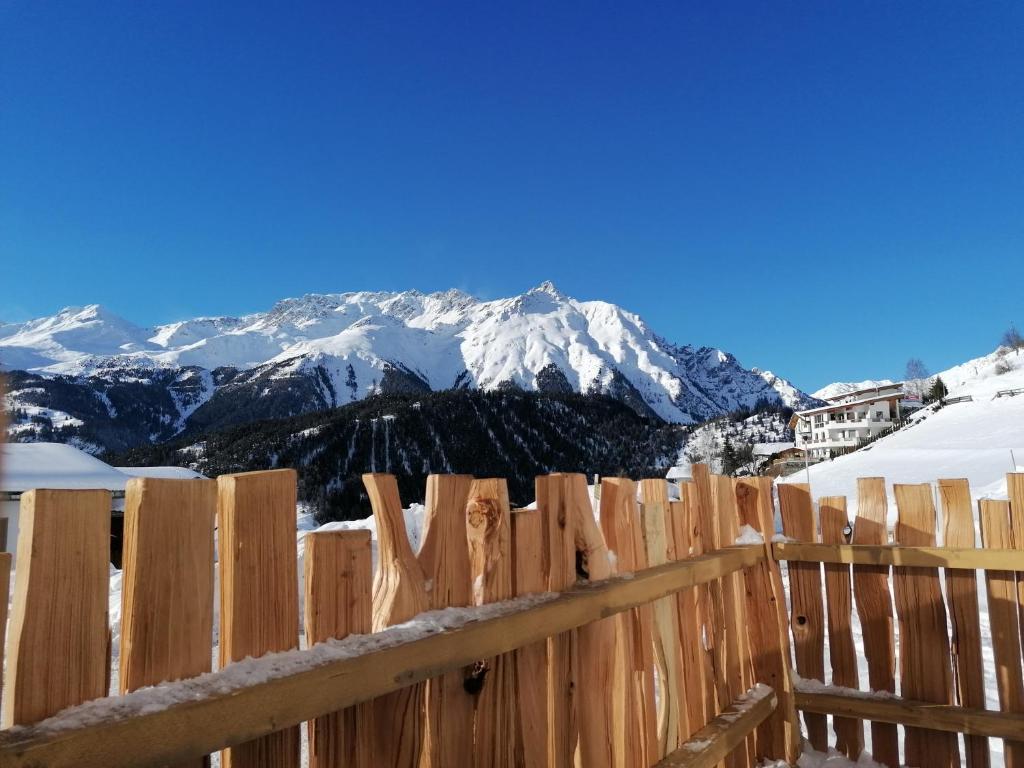 ein Holzzaun mit einem schneebedeckten Berg im Hintergrund in der Unterkunft Apart Paul in Nauders