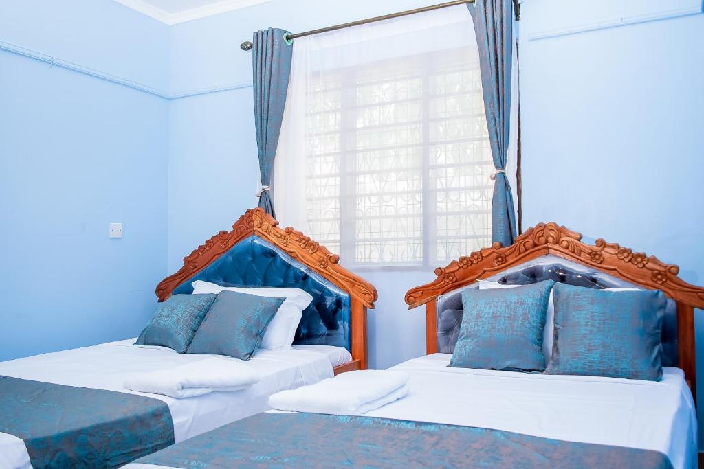 dwa łóżka w pokoju niebiesko-białym w obiekcie Dondoo's Paradise- Perfect Vacation Home w mieście Kilifi