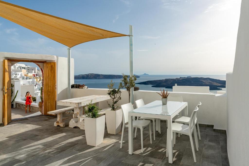 a table and chairs on a balcony with a view of the ocean at Akron Cliff Suite in Fira