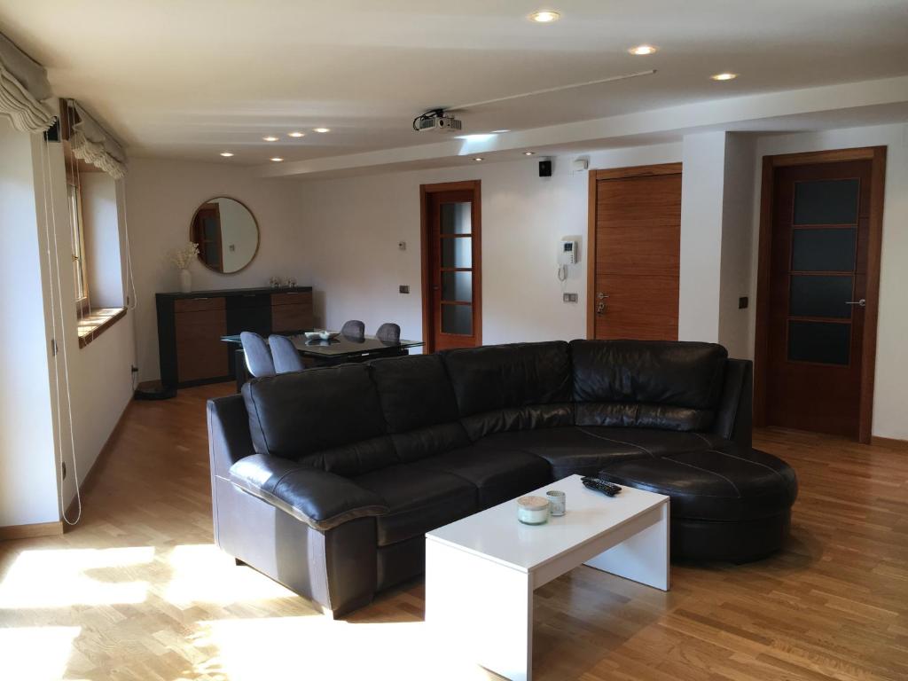 - un salon avec un canapé en cuir noir et une table dans l'établissement Bossost Apartamento casa blasi, à Bossost