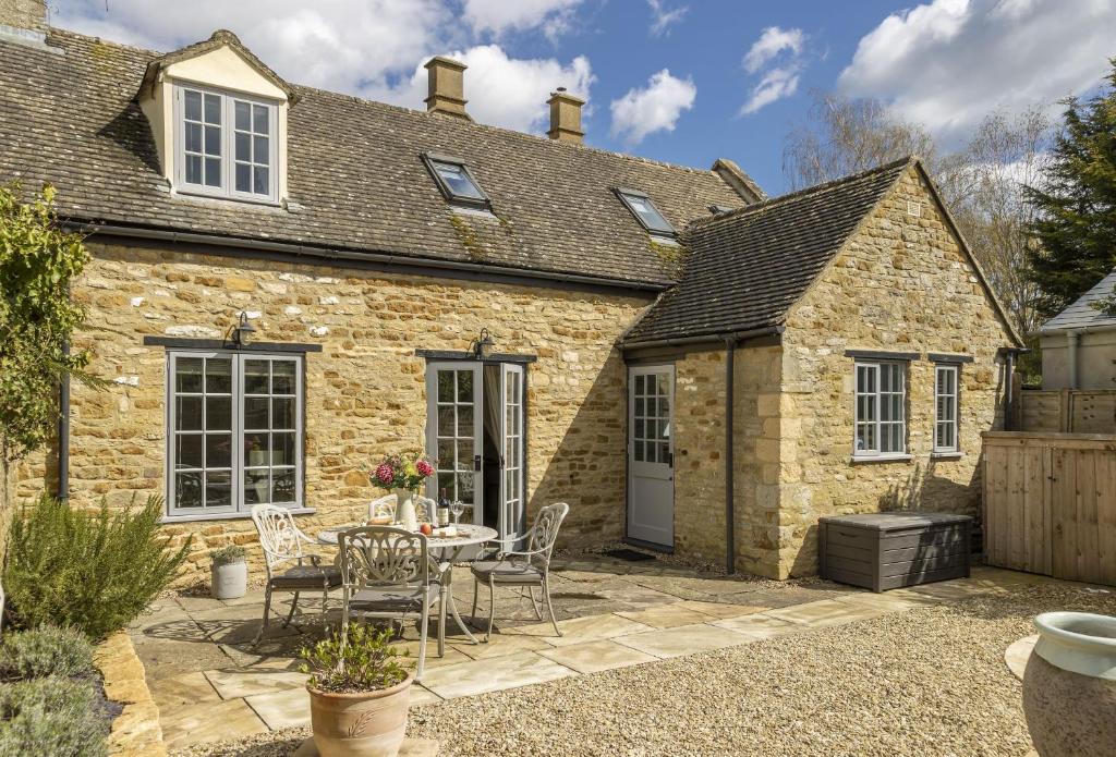 a stone cottage with a table and chairs in front of it at Old Stable Cottage in Kingham