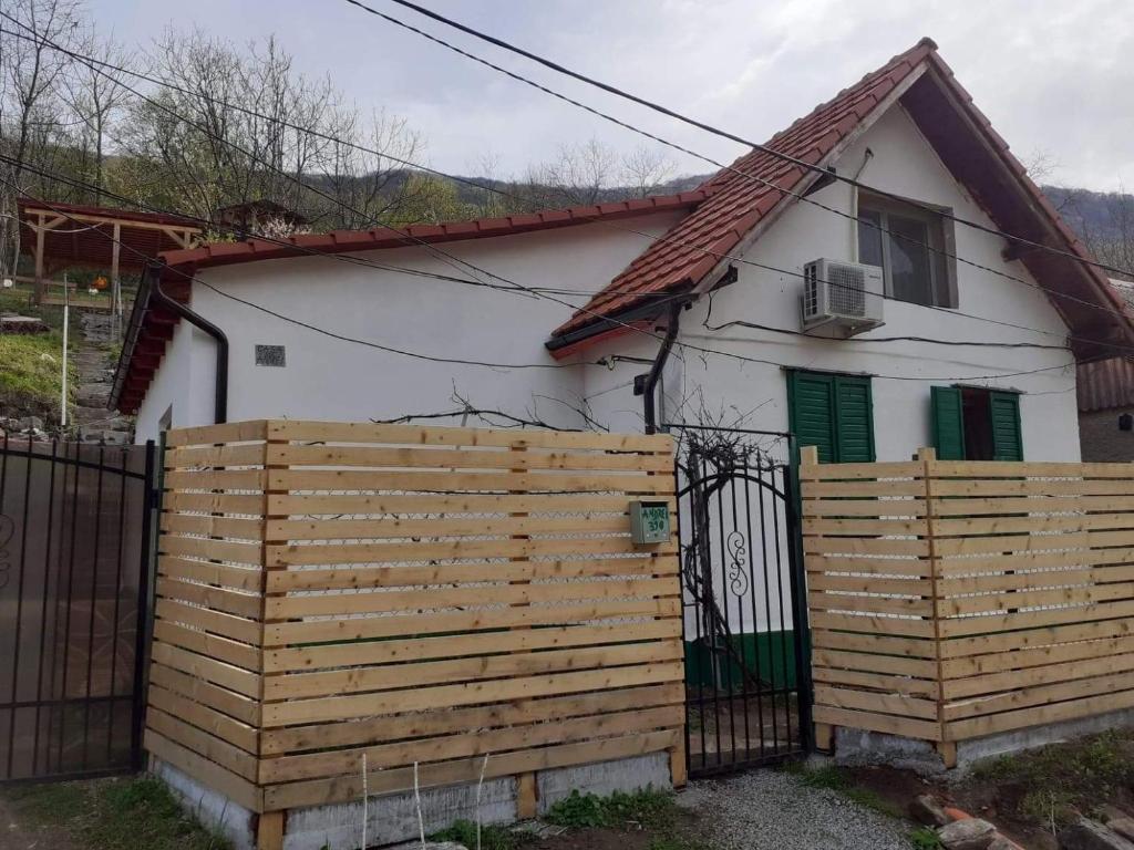 a small white house with a wooden fence at Andrei in Sasca Montană