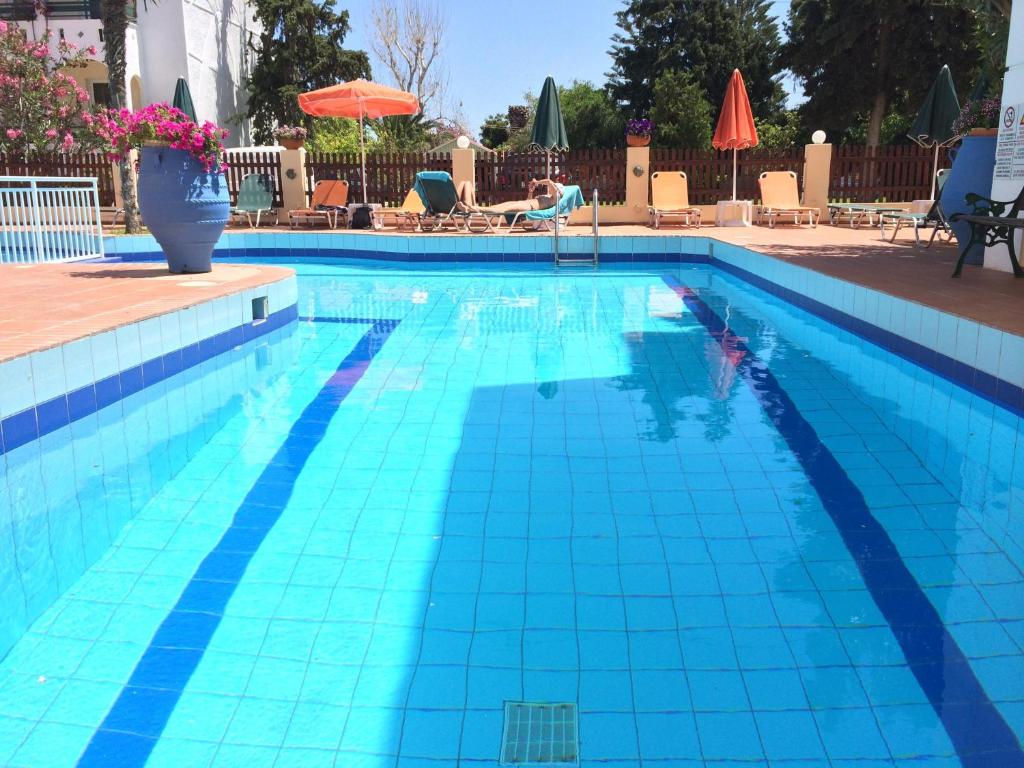 a blue swimming pool with a person in the water at Bueno Hotel in Platanes