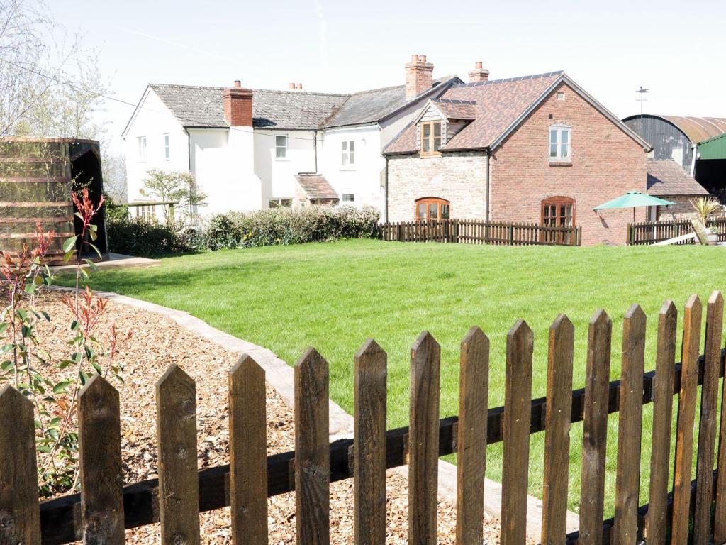 una cerca frente a una casa con un patio en The Cider House, en Leominster