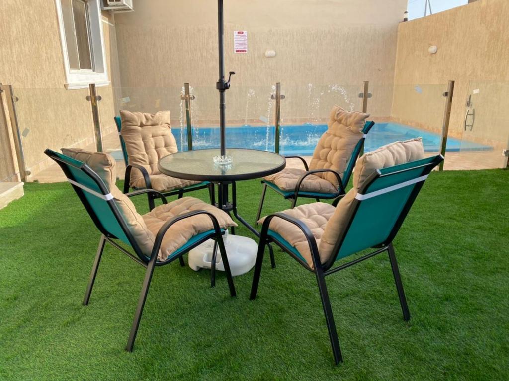 - un groupe de chaises, une table et une piscine dans l'établissement فيلا أمواج الشاطىء Amoaj beach, à Rayyis