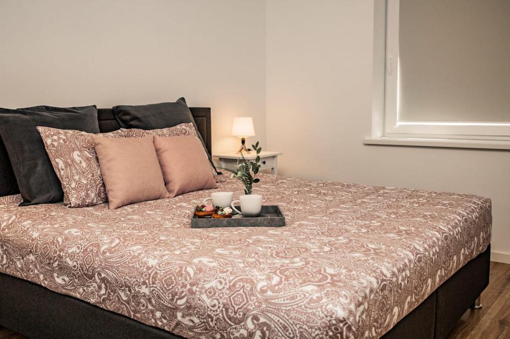 a bed with a tray with two candles on it at MOOD Apartamenti Kuldīgā in Kuldīga