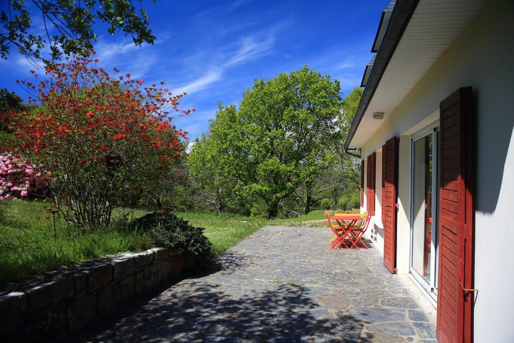 a pathway next to a house with a red door at Aux Arbres Chanteurs in Ploulech