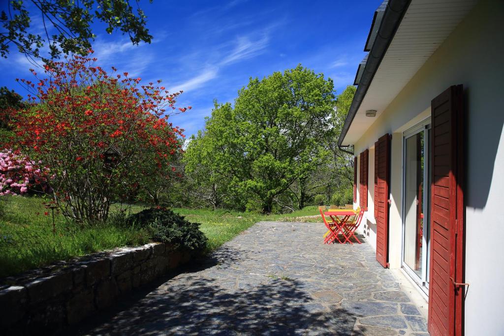 un chemin à côté d'une maison avec une porte rouge dans l'établissement Aux Arbres Chanteurs, à Ploulech