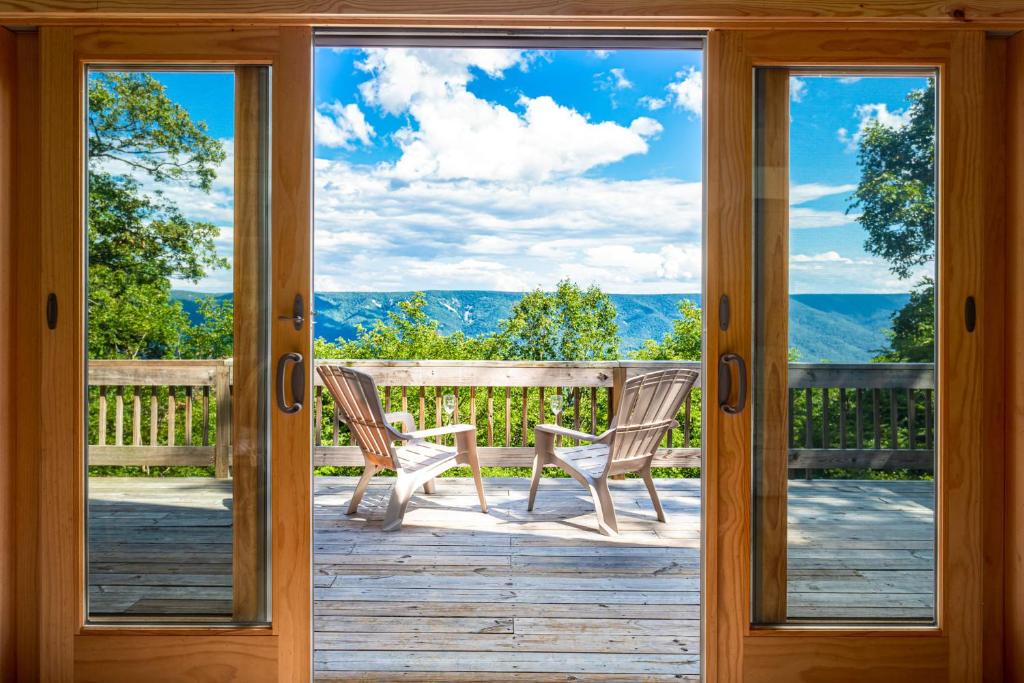 une porte menant à une terrasse couverte avec 2 chaises dans l'établissement Amazing Views, Hot Tub, Huge Deck at Chalet Cabin, à Great Cacapon