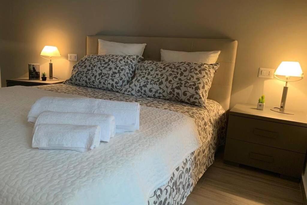 una camera da letto con un grande letto con lenzuola e cuscini bianchi di Loft Orlando 52 a Catania