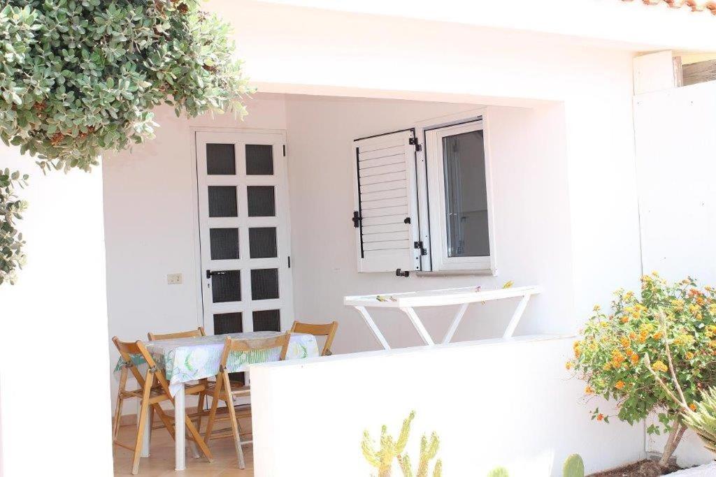 ein weißes Haus mit einem Tisch und Stühlen auf einer Terrasse in der Unterkunft TELLINA PALMARE BEACH in Lampedusa