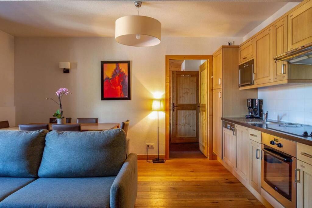 a living room with a blue couch and a kitchen at Appartement vue sur les montagnes Suisses in Vallorcine