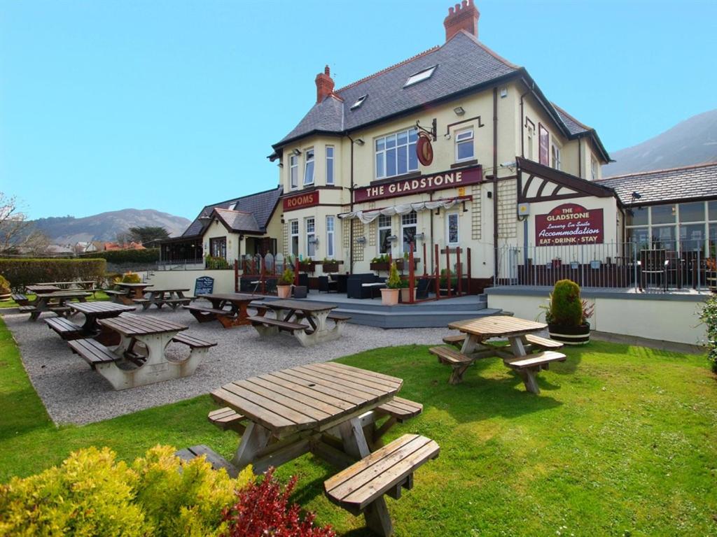 un groupe de tables de pique-nique devant un bâtiment dans l'établissement The Gladstone, à Conwy