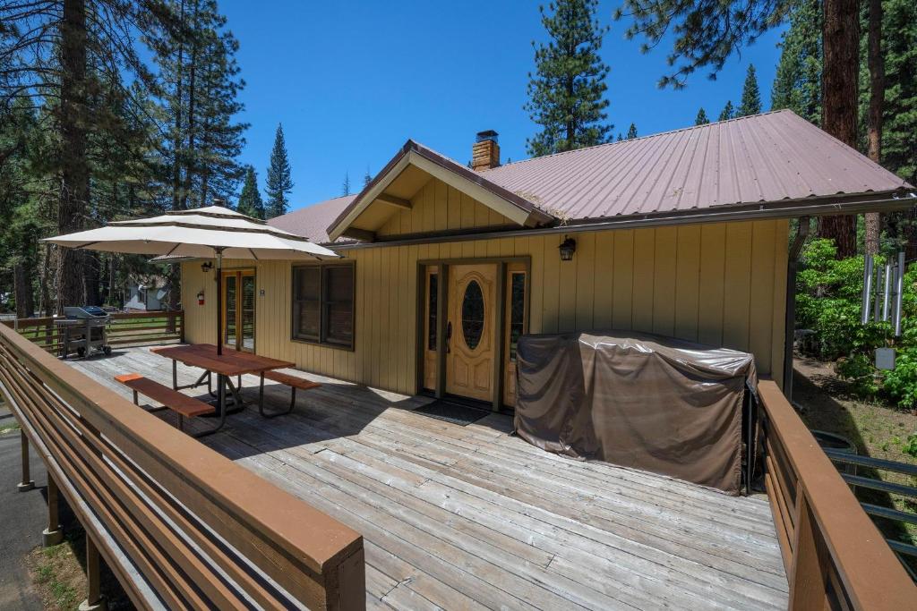 a house with a deck with a table and an umbrella at Apple Tree Bear House in Yosemite West