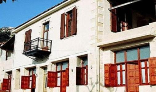 - un bâtiment blanc avec des fenêtres rouges et un balcon dans l'établissement Enatha, à Argyroupolis