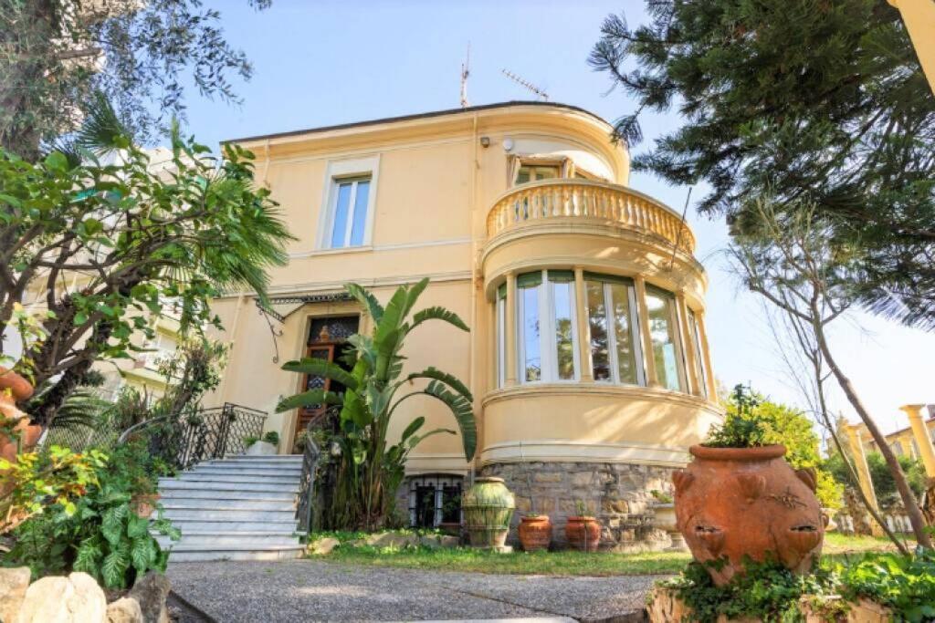 Una gran casa amarilla con un jarrón delante. en Villa Vale en San Remo
