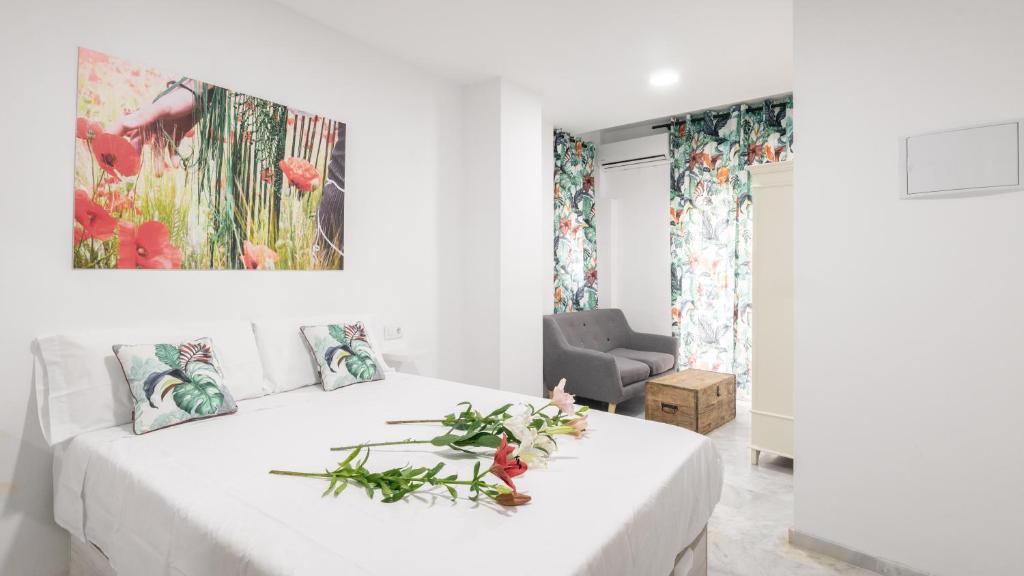 a white bedroom with a white bed with flowers on it at Guesthouse Apartment Seville La Flamenka in Seville