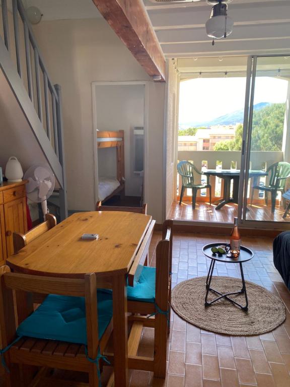 a dining room with a wooden table and chairs and a balcony at Plein Sud By Bellavista - 400 m de la plage - terrasse - parking in Argelès-sur-Mer