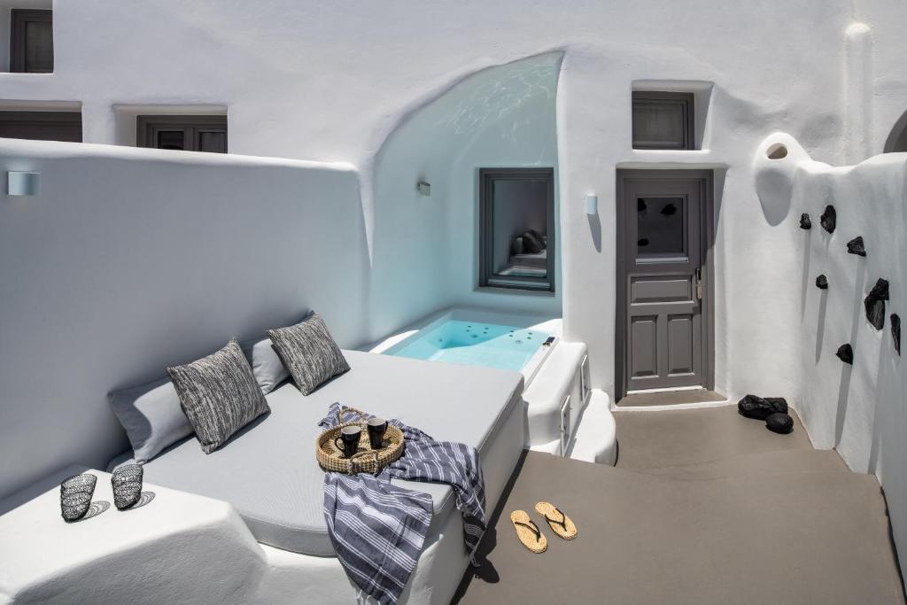 Habitación blanca con bañera, cama y zapatos en Deep in cave suites, en Fira