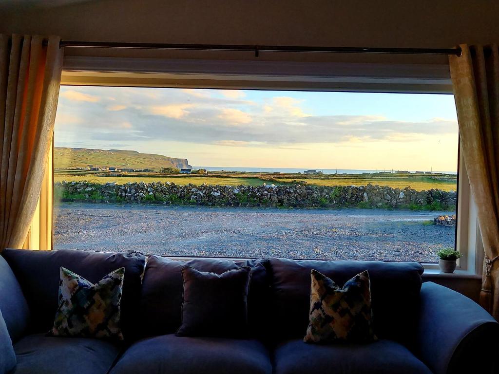 eine Couch vor einem großen Fenster in der Unterkunft Cliffs View Self Catering @ Limestone Lodge in Doolin