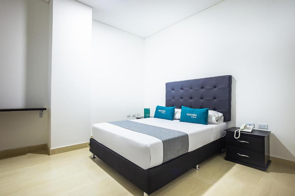 a bedroom with a large bed with blue pillows at Ayenda Hotel Trinidad in Montería