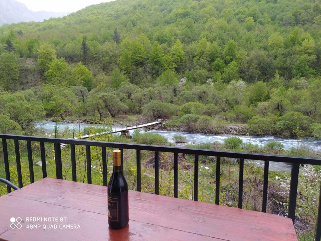 a bottle of wine sitting on a wooden table overlooking a river at Mileta&Vasilije in Mojkovac