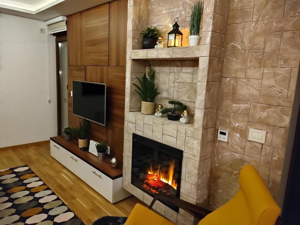 sala de estar con chimenea de piedra y TV en Casa di Stefano apartment & SPA, en Zlatibor