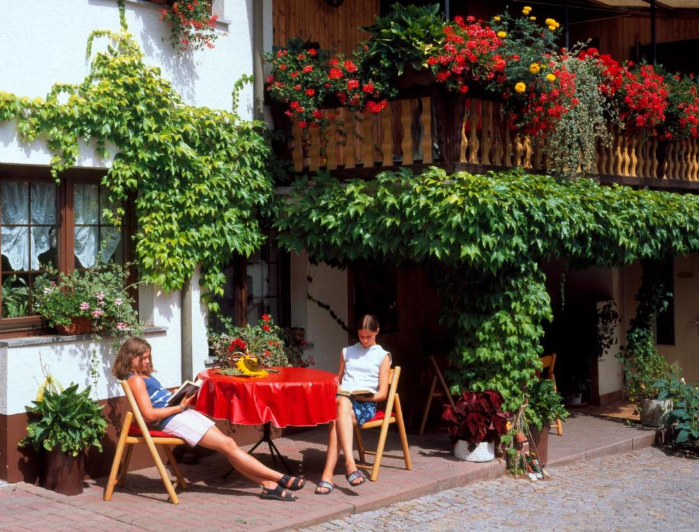 dos personas sentadas en una mesa frente a un edificio en Landpension Risch, en Ilmenau