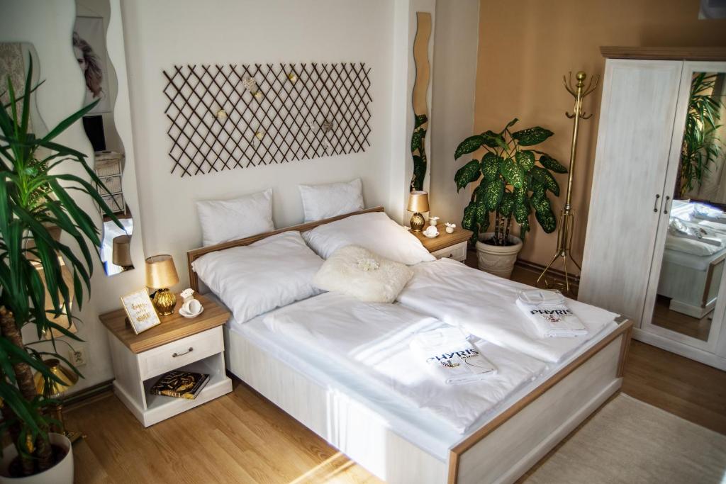 Beauty-Spa Apartment في ديشين: غرفة نوم بسرير من الشراشف البيضاء والنباتات