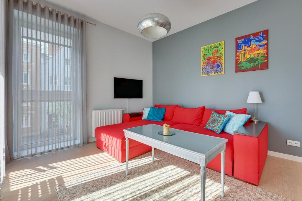 salon z czerwoną kanapą i stołem w obiekcie Comfort Apartments Kwartał Kamienic w Gdańsku