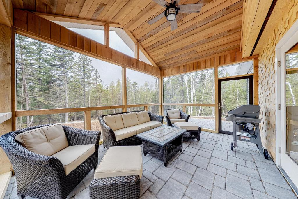 a screened in porch with furniture and a grill at Creek Cottage in Bass Harbor