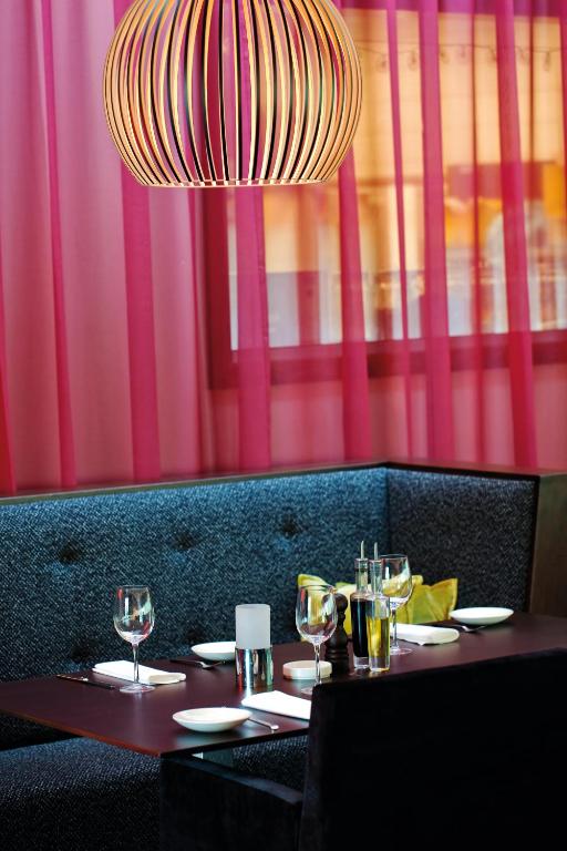 a table with glasses and a chandelier in a restaurant at Radisson Blu Hotel, Trondheim Airport in Stjoerdal