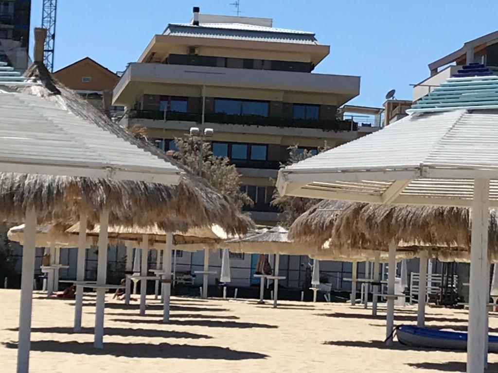 - un groupe de parasols en paille sur une plage avec un bâtiment dans l'établissement Alma Luxury suite, à Pescara