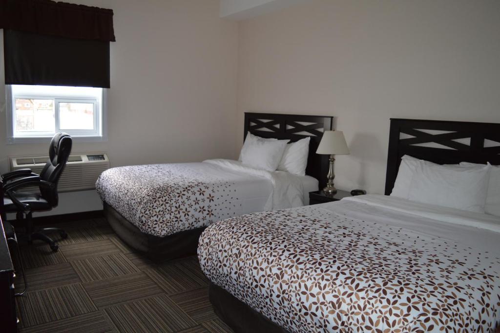 a hotel room with two beds and a chair at Auberge MacDonald Guest Inn in Iroquois Falls