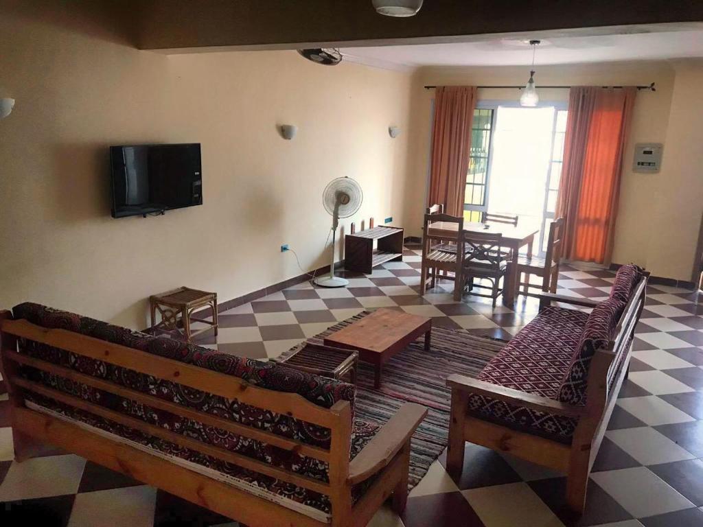 a living room with benches and a tv on the wall at Dahab Vibes Villas in Dahab