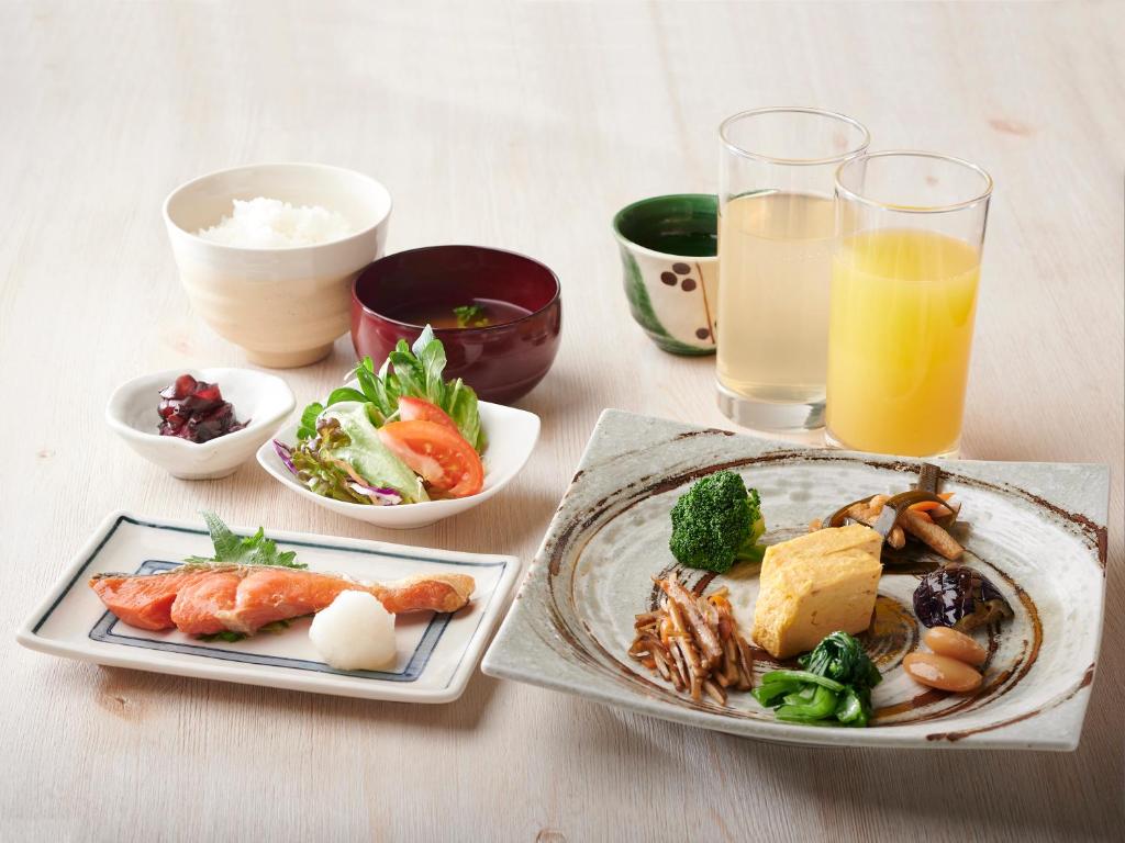 a table with two plates of food and a glass of orange juice at APA Hotel Nishifunabashi Ekimae in Funabashi