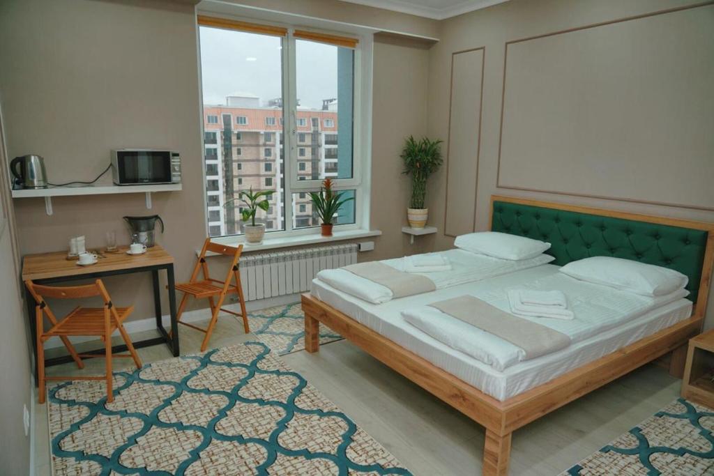Halal Apart Hotel Almaty في ألماتي: غرفة نوم بسرير ومكتب ونافذة