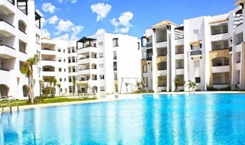 uma grande piscina em frente a alguns edifícios de apartamentos em Asilah Marina Golf em Asilah