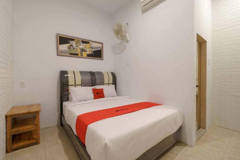 een slaapkamer met een bed in een witte kamer bij RedDoorz @ Mutiara Residence in Pulauberayan Dadap