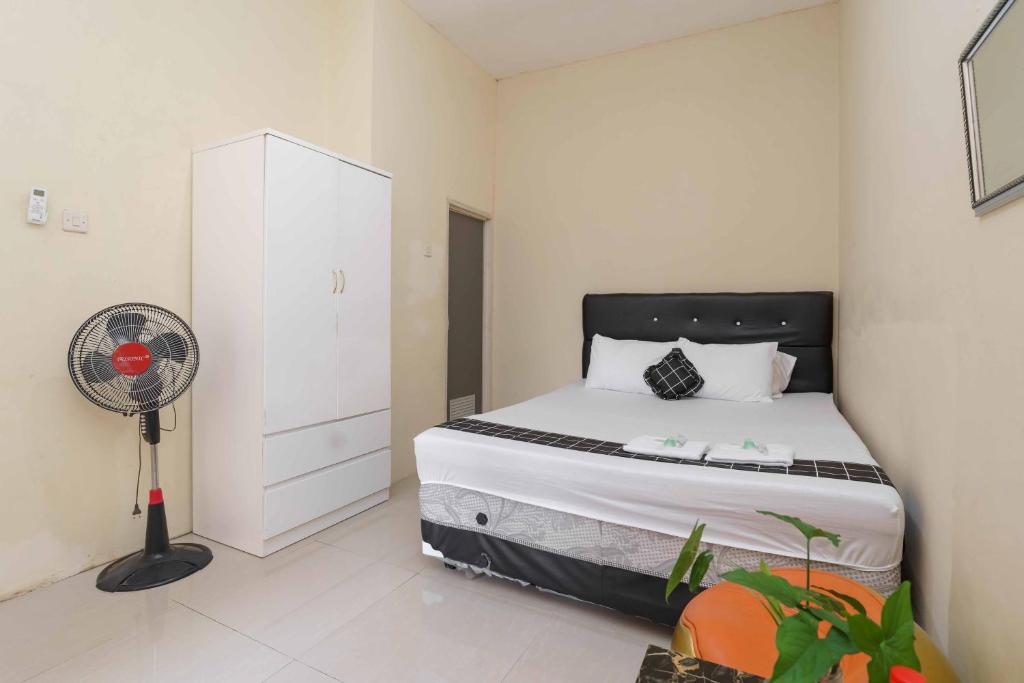 - une petite chambre avec un lit et un ventilateur dans l'établissement Madinah House Syariah Mitra RedDoorz, à Depok