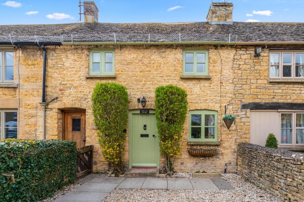 a brick house with a green door at Forsythia Cottage in Bourton on the Water