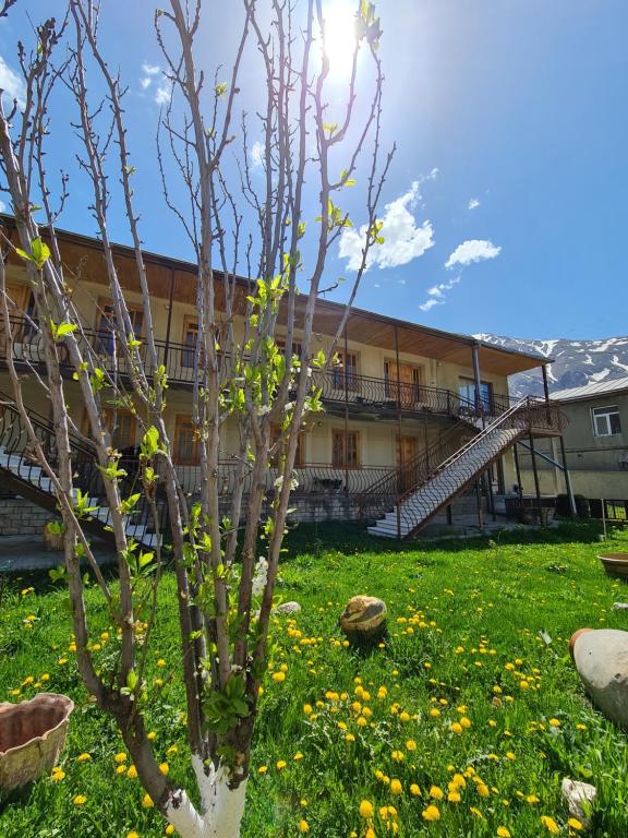 un edificio con un árbol en un campo de flores en Sunny Mountain House en Stepantsminda