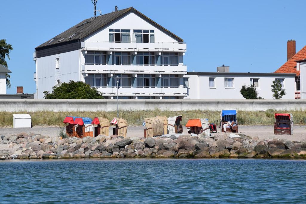 a white building with a row of chairs next to the water at Hotel Thode in Dahme