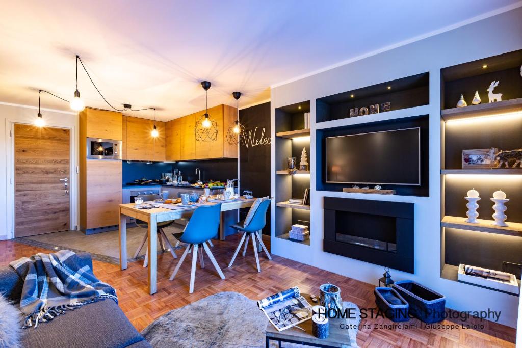 uma sala de estar com uma mesa de jantar e uma televisão em Hostdomus - Il Cerbiatto Apartment em Sestriere